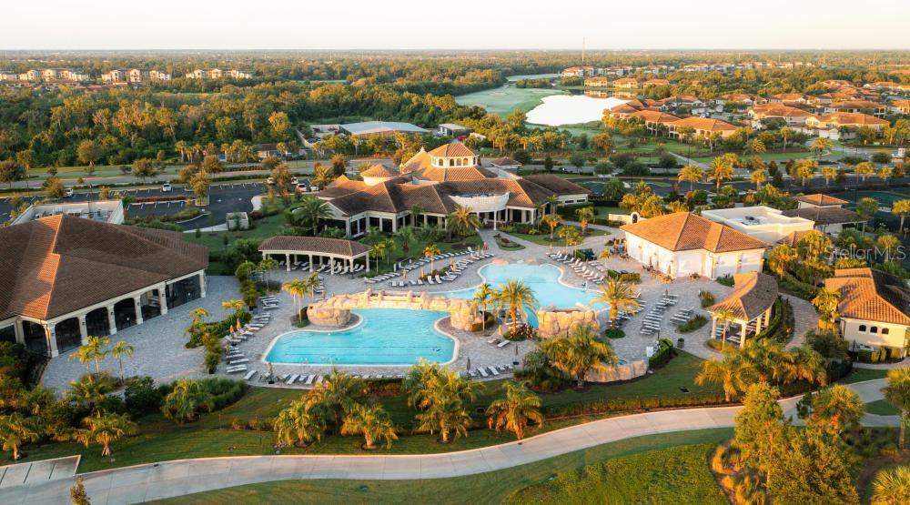 An aerial view of a community clubhouse featuring a large swimming pool and surrounding landscaping — 17724 GAWTHROP DRIVE UNIT 208, BRADENTON, FL