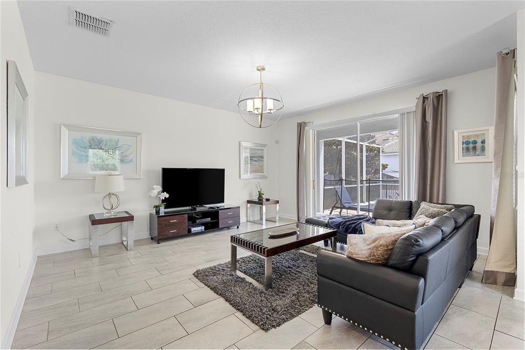 A living room features light tile floors, a dark leather sectional, and a sliding glass door — 1559 FLANGE DRIVE, DAVENPORT, FL