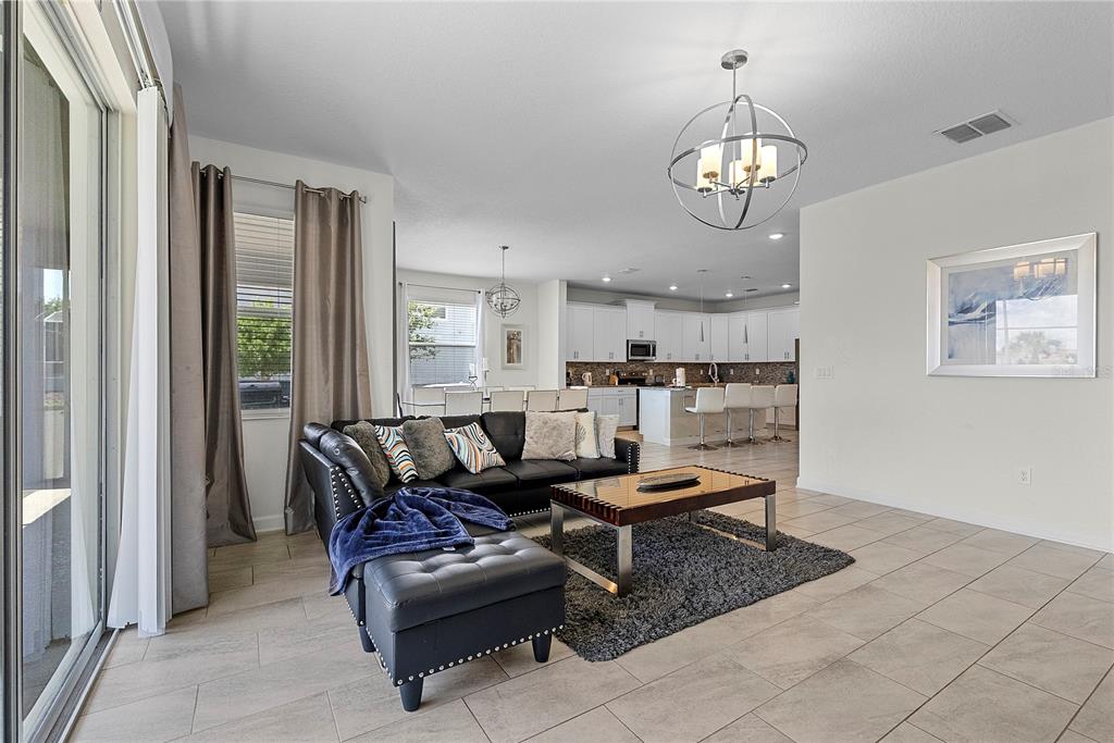 A living room with a black sofa and coffee table opens into a white kitchen — 1559 FLANGE DRIVE, DAVENPORT, FL