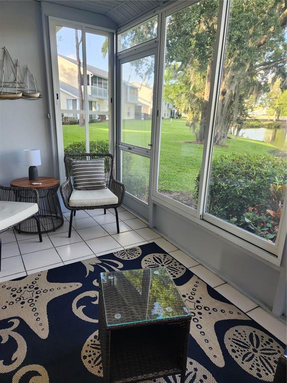 A screened-in porch with tile floors, wicker furniture, and a view of a pond — 5515 FAIR OAKS STREET UNIT 5515, BRADENTON, FL