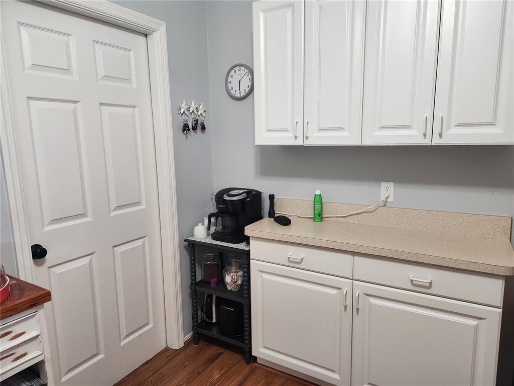 A kitchen area features white cabinets, a beige countertop, a coffee maker, and a door — 5515 FAIR OAKS STREET UNIT 5515, BRADENTON, FL