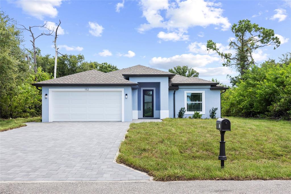 A light blue single-story house features a paved driveway, a two-car garage, and landscaping — 152 ALBATROSS ROAD, ROTONDA WEST, FL