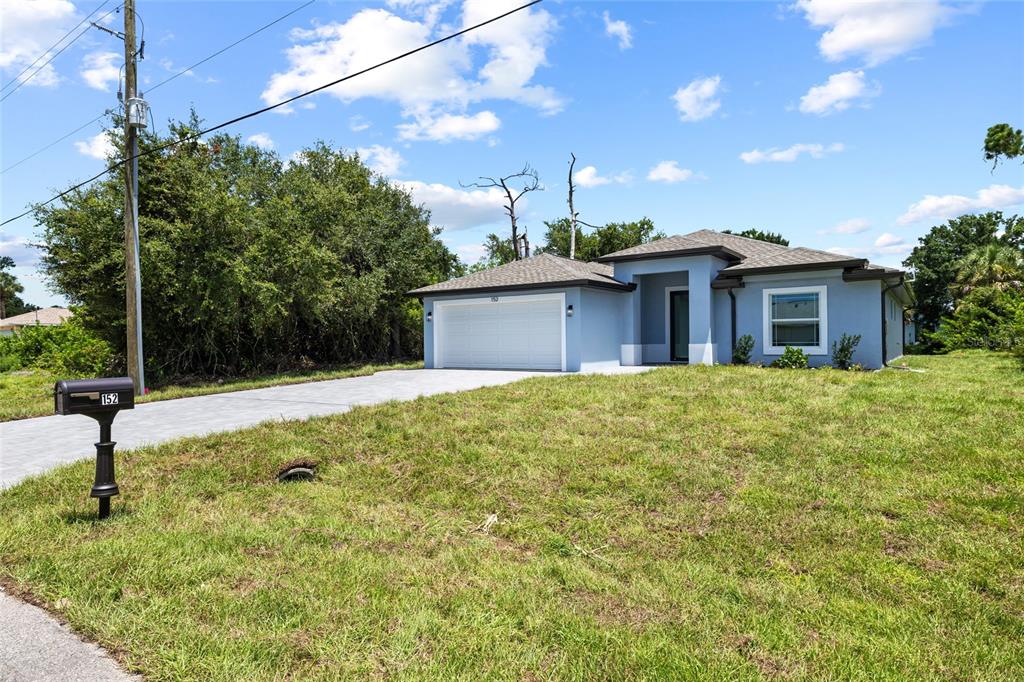 A light blue single-story house with a two-car garage and a paved driveway — 152 ALBATROSS ROAD, ROTONDA WEST, FL