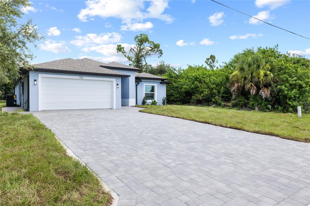 A light blue single-story house features a paved driveway and a two-car garage — 152 ALBATROSS ROAD, ROTONDA WEST, FL