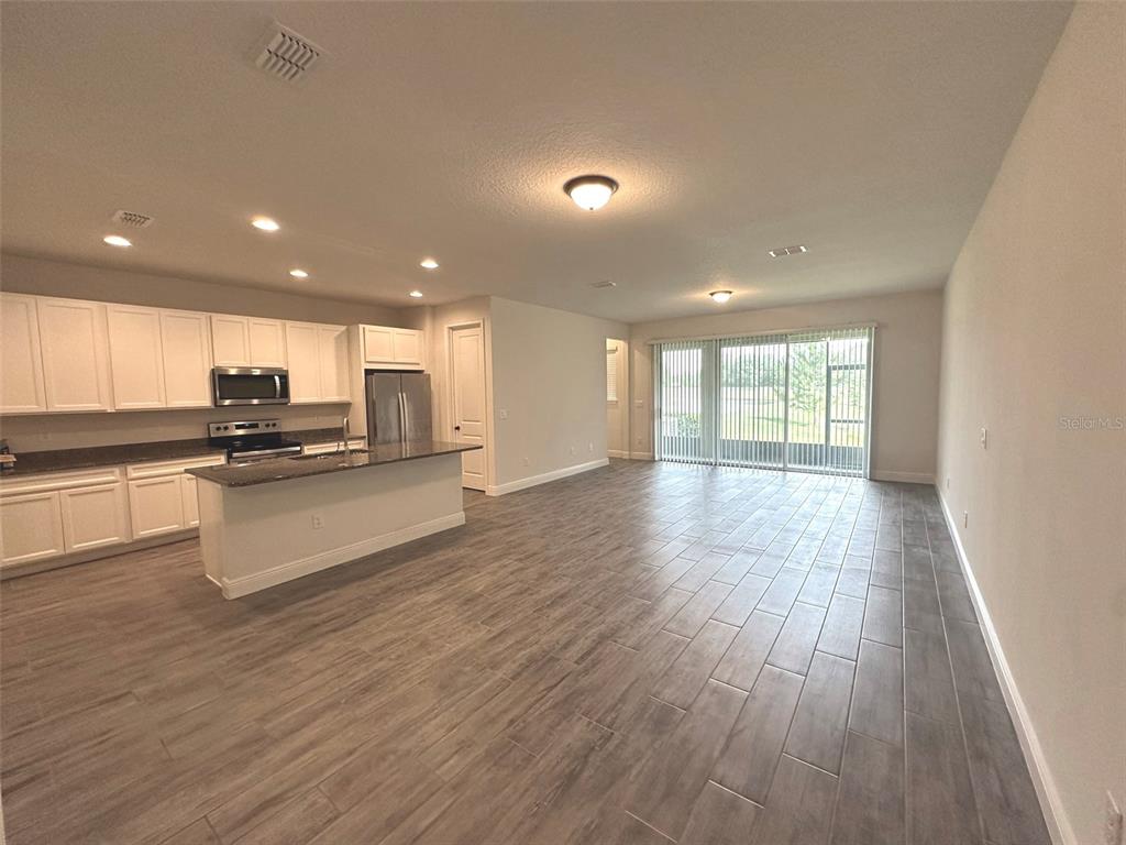 An open-concept kitchen and living area features white cabinetry, a kitchen island, and tile flooring — 11634 CAMBIUM CROWN DRIVE, RIVERVIEW, FL
