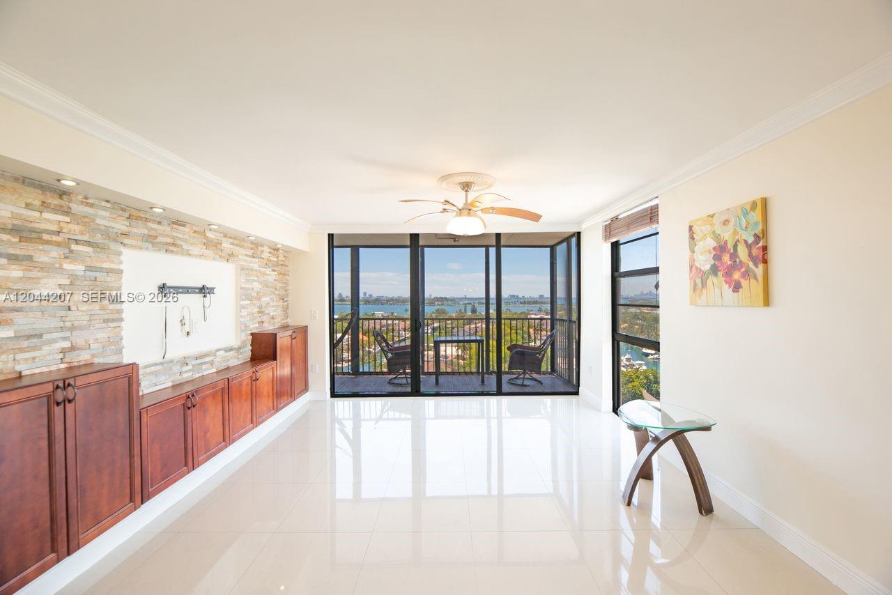 A living room features a stone accent wall, wooden cabinetry, and a balcony with water views — 2500 NE 135th St # C1011, North Miami FL 33181, NORTH MIAMI, FL