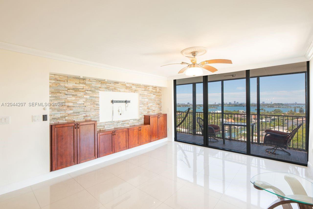 A living room features a stone accent wall, wooden cabinetry, and a balcony overlooking water — 2500 NE 135th St # C1011, North Miami FL 33181, NORTH MIAMI, FL