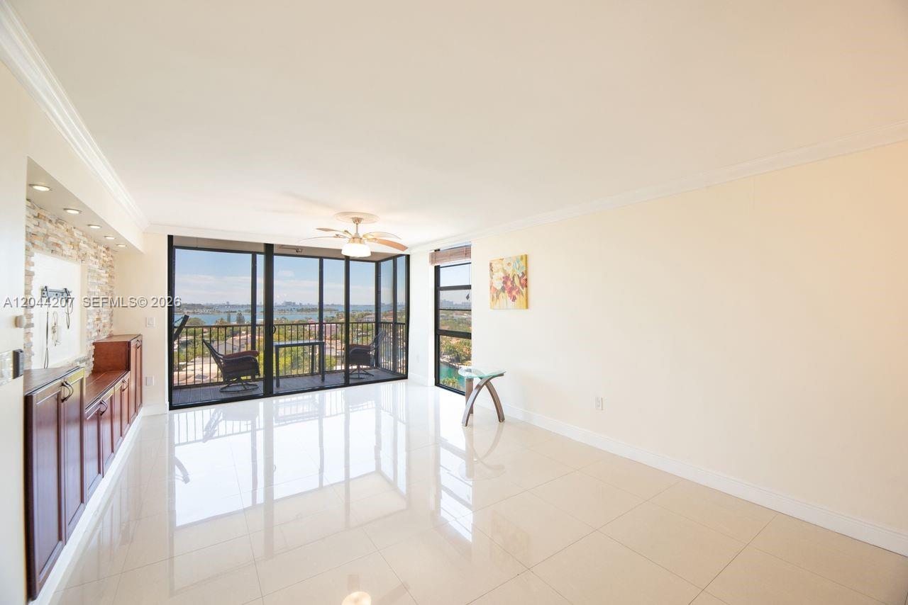 A bright living room features white tile floors, a stone accent wall, and a balcony view — 2500 NE 135th St # C1011, North Miami FL 33181, NORTH MIAMI, FL