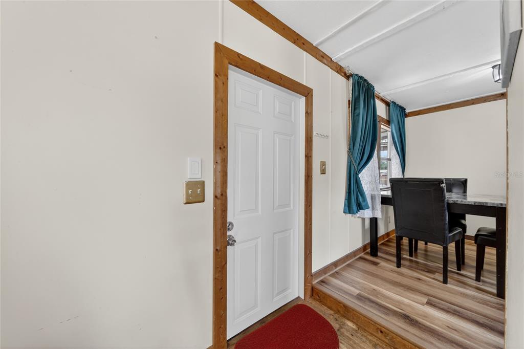 A white door with wood trim opens into a dining area with wood-look flooring — 4710 VILLAGE DRIVE, LAKELAND, FL