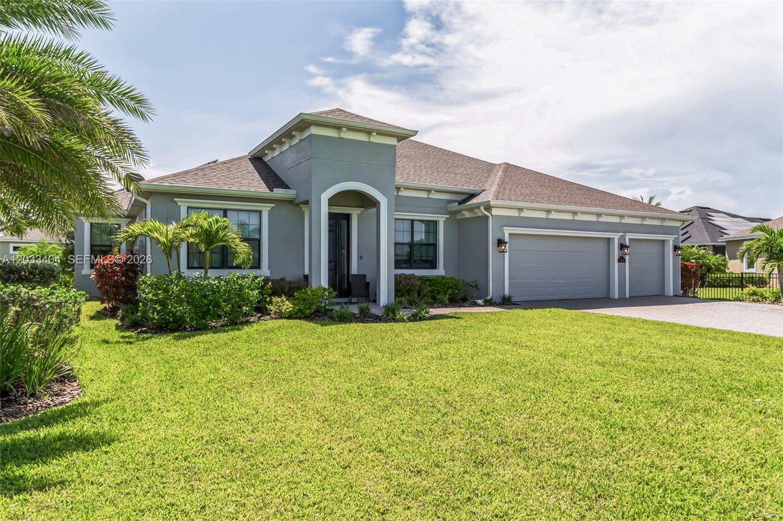 A single-story gray house with a three-car garage and a front entryway arch — MELBOURNE, FL