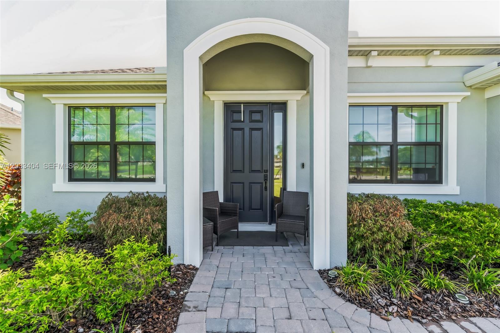 The front exterior of a house features a dark door, arched entryway, and paved walkway — MELBOURNE, FL