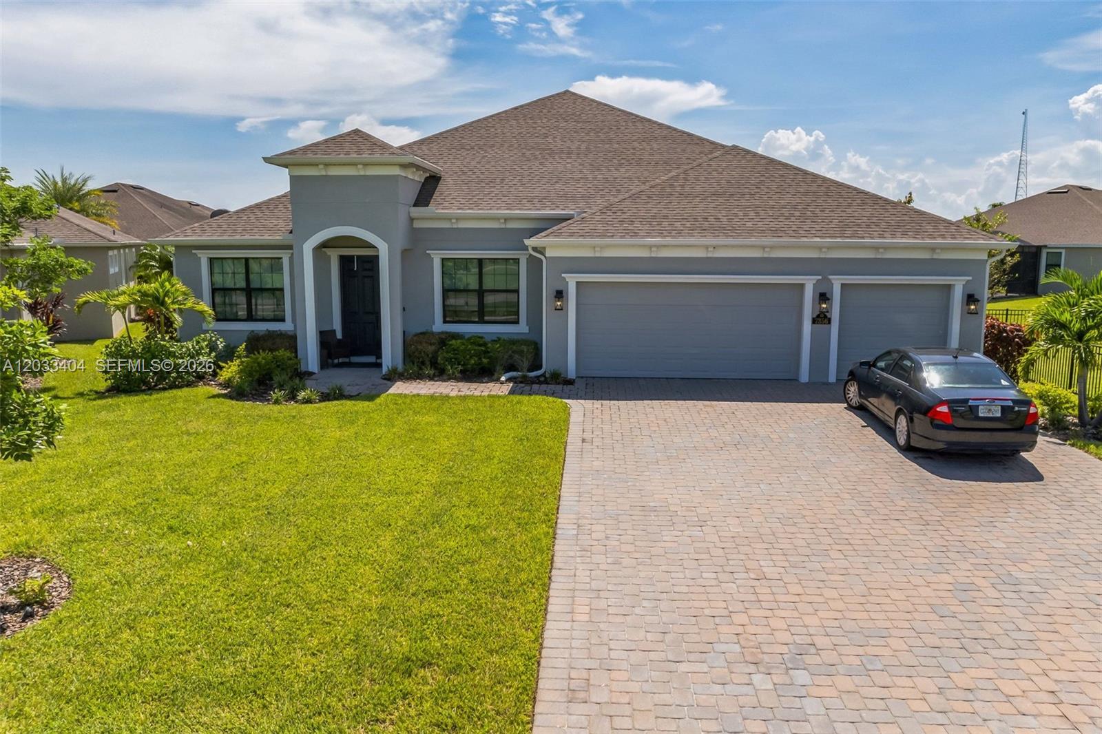 A single-story gray house with a paver driveway and a three-car garage — MELBOURNE, FL