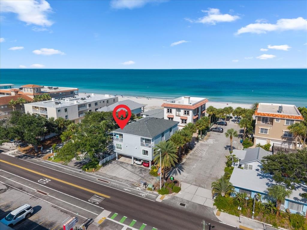 An aerial view shows a multi-story light blue building located near a sandy beach — 112 GULF BOULEVARD UNIT A, INDIAN ROCKS BEACH, FL