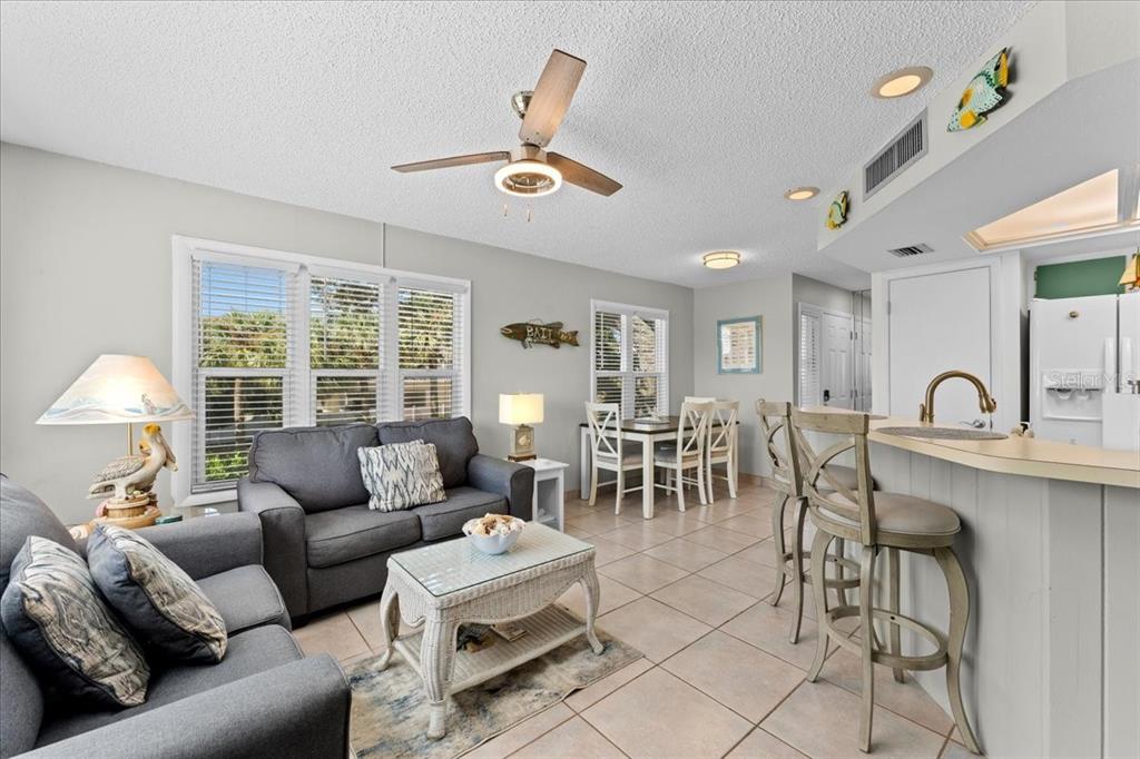 A living room and dining area feature tile floors, a ceiling fan, and bar seating — 112 GULF BOULEVARD UNIT A, INDIAN ROCKS BEACH, FL