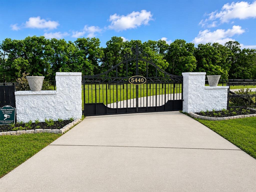 A black metal gate with the number 5440 is flanked by white stone pillars — 5440 NE 31ST TERRACE, OCALA, FL