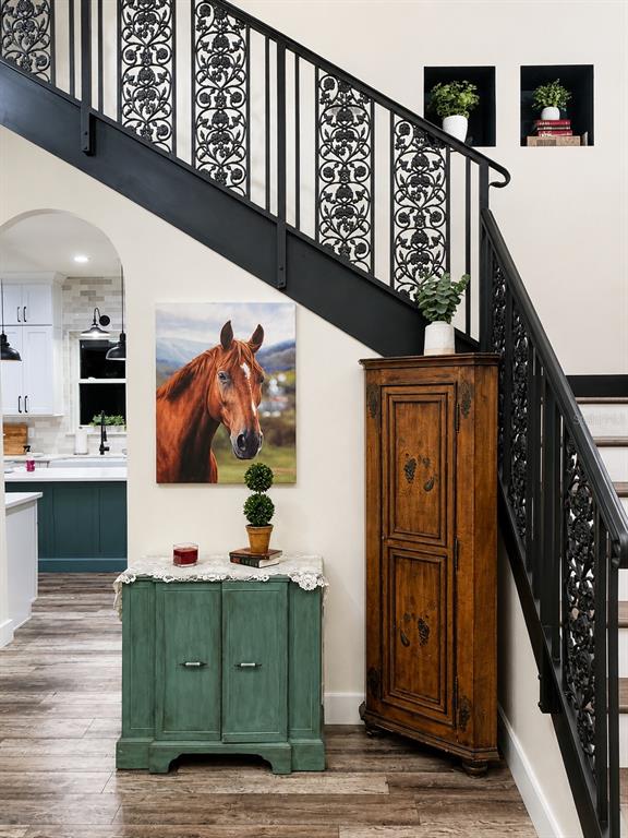 A staircase with ornate black metal railings stands beside a green cabinet and corner cupboard — 5440 NE 31ST TERRACE, OCALA, FL