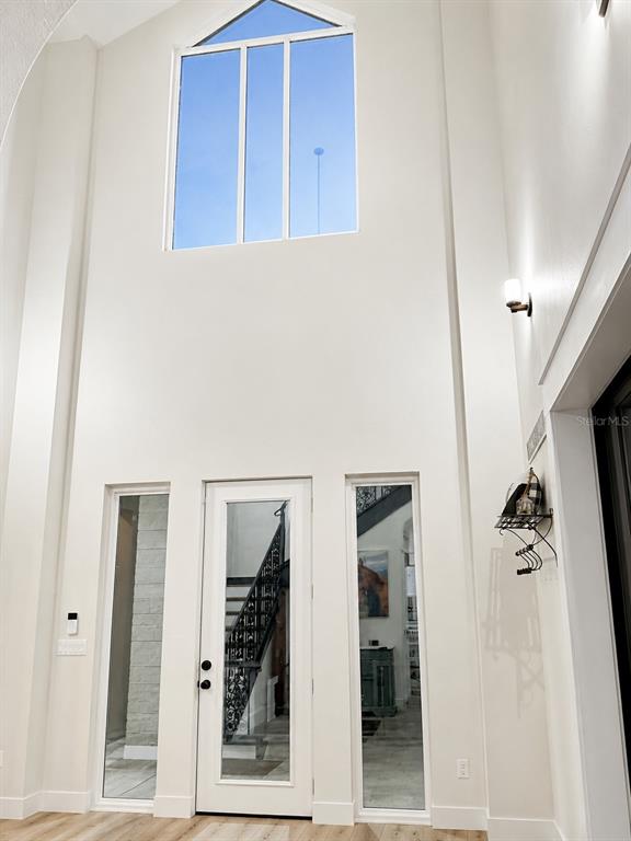 A bright entryway features a tall vaulted ceiling, a glass-paneled front door, and side windows — 5440 NE 31ST TERRACE, OCALA, FL