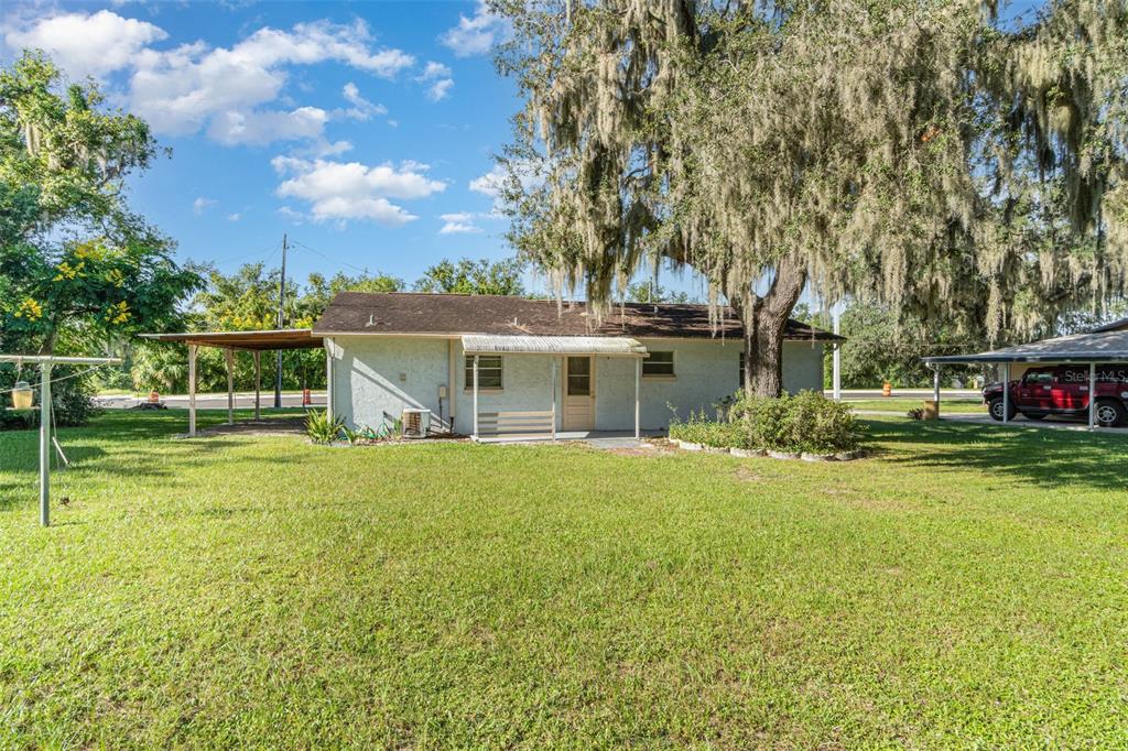 The exterior of a single-story house features a covered patio and a large oak tree — 918 W MAGNOLIA STREET, ARCADIA, FL