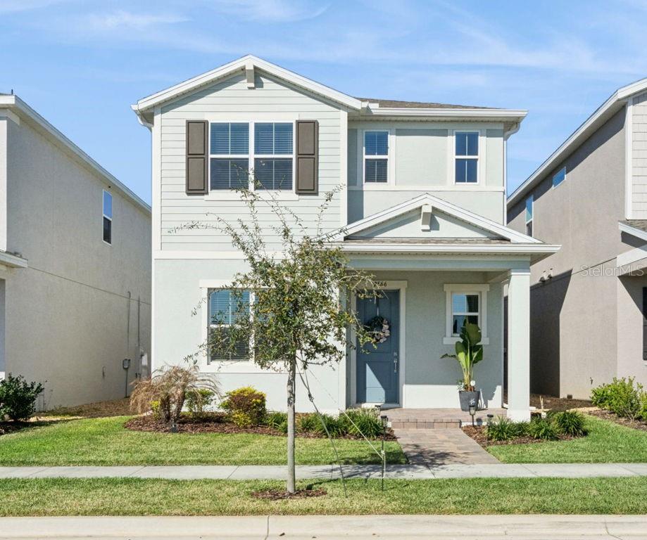 A two-story house with light green siding, a covered front porch, and a paved walkway — 12566 WESTHAVEN OAK DRIVE, WINTER GARDEN, FL