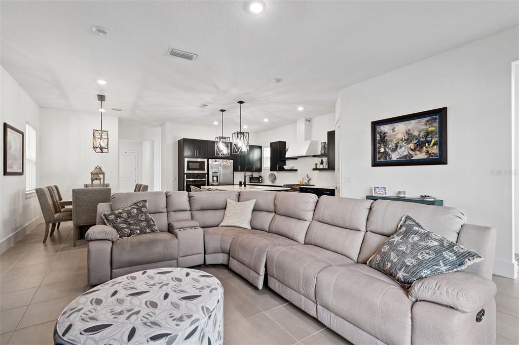 A spacious open-concept living room features a large sectional sofa, dining area, and modern kitchen — 12566 WESTHAVEN OAK DRIVE, WINTER GARDEN, FL