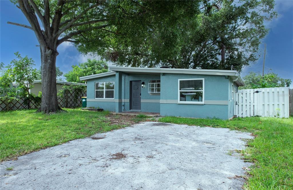 A single-story teal house with a concrete driveway and a large tree in the yard — 10276 121ST AVENUE, LARGO, FL