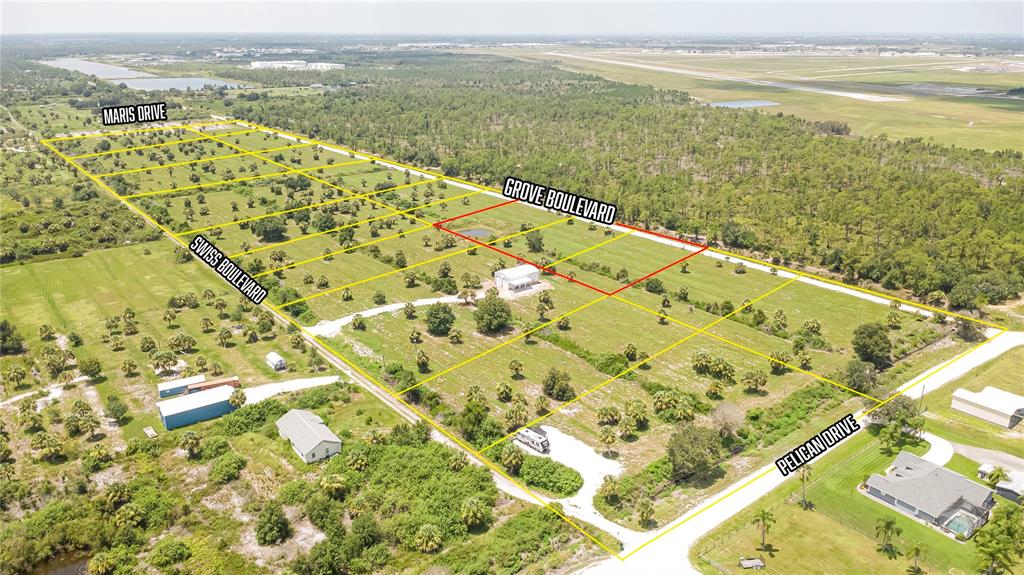 An aerial view shows a large, undeveloped plot of land with yellow grid lines — 7074 GROVE BOULEVARD, PUNTA GORDA, FL