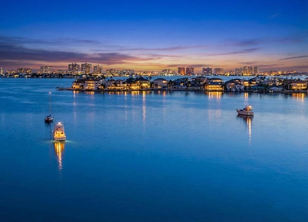 An aerial view of a waterfront neighborhood with boats at dusk under a sunset sky — 100 BLUFF VIEW DRIVE UNIT 608C, BELLEAIR BLUFFS, FL