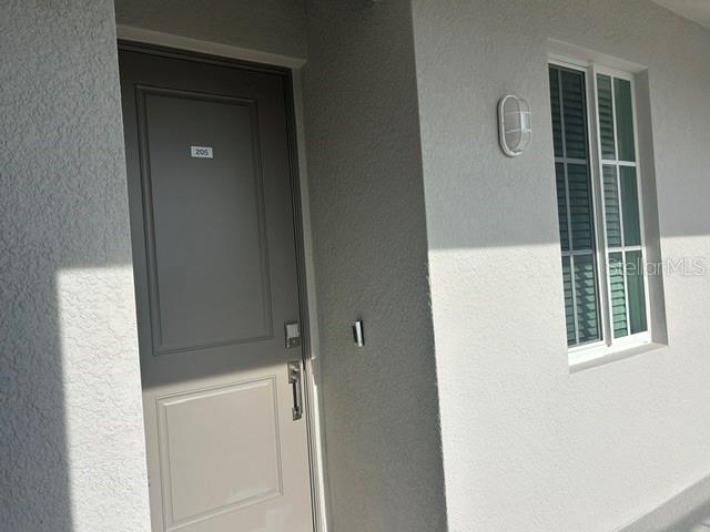 A gray door labeled 205 sits next to a window and an outdoor light fixture — 17570 OPAL SAND DRIVE UNIT 205, VENICE, FL