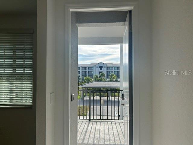An open doorway leads to a balcony overlooking a parking structure and apartment building — 17570 OPAL SAND DRIVE UNIT 205, VENICE, FL