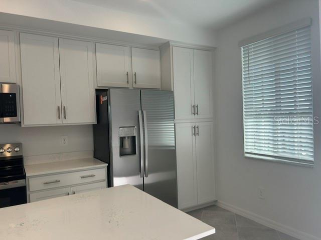 A kitchen features white cabinets, stainless steel appliances, and a white quartz-topped island — 17570 OPAL SAND DRIVE UNIT 205, VENICE, FL