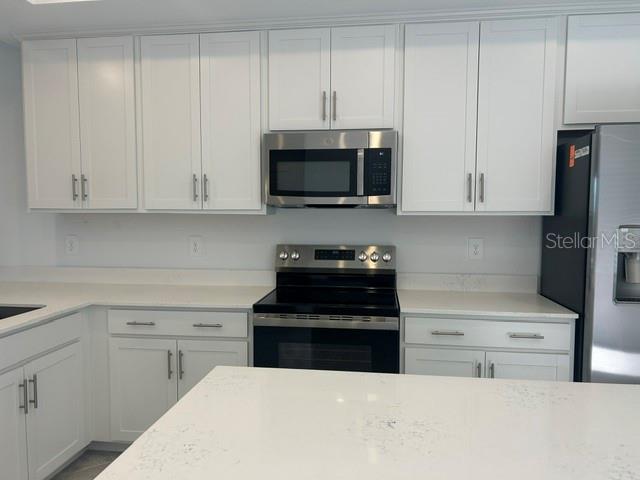 A kitchen features white cabinets, a quartz countertop, and stainless steel appliances — 17570 OPAL SAND DRIVE UNIT 205, VENICE, FL