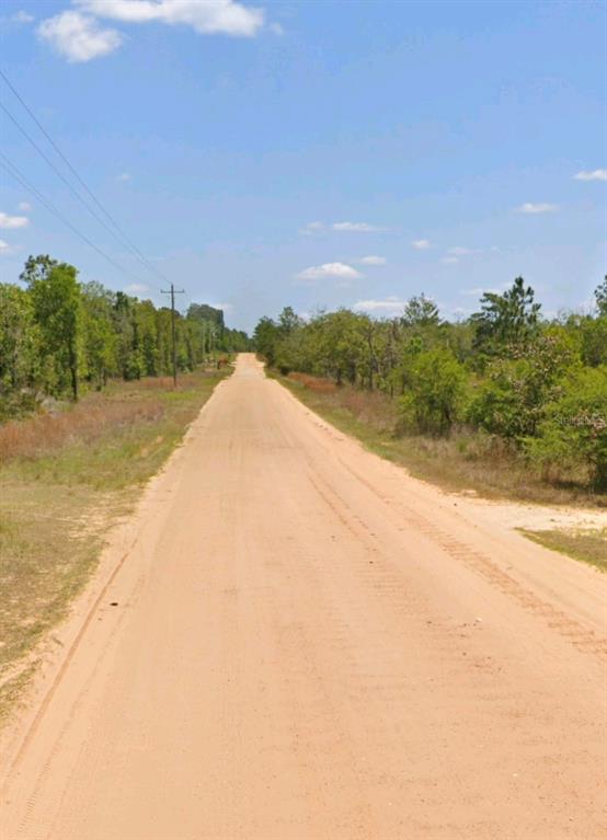A long, straight dirt road stretches through a rural landscape with trees and power lines — LOT 14 15 16 AND 17 IDAHO AVENUE, HAWTHORNE, FL