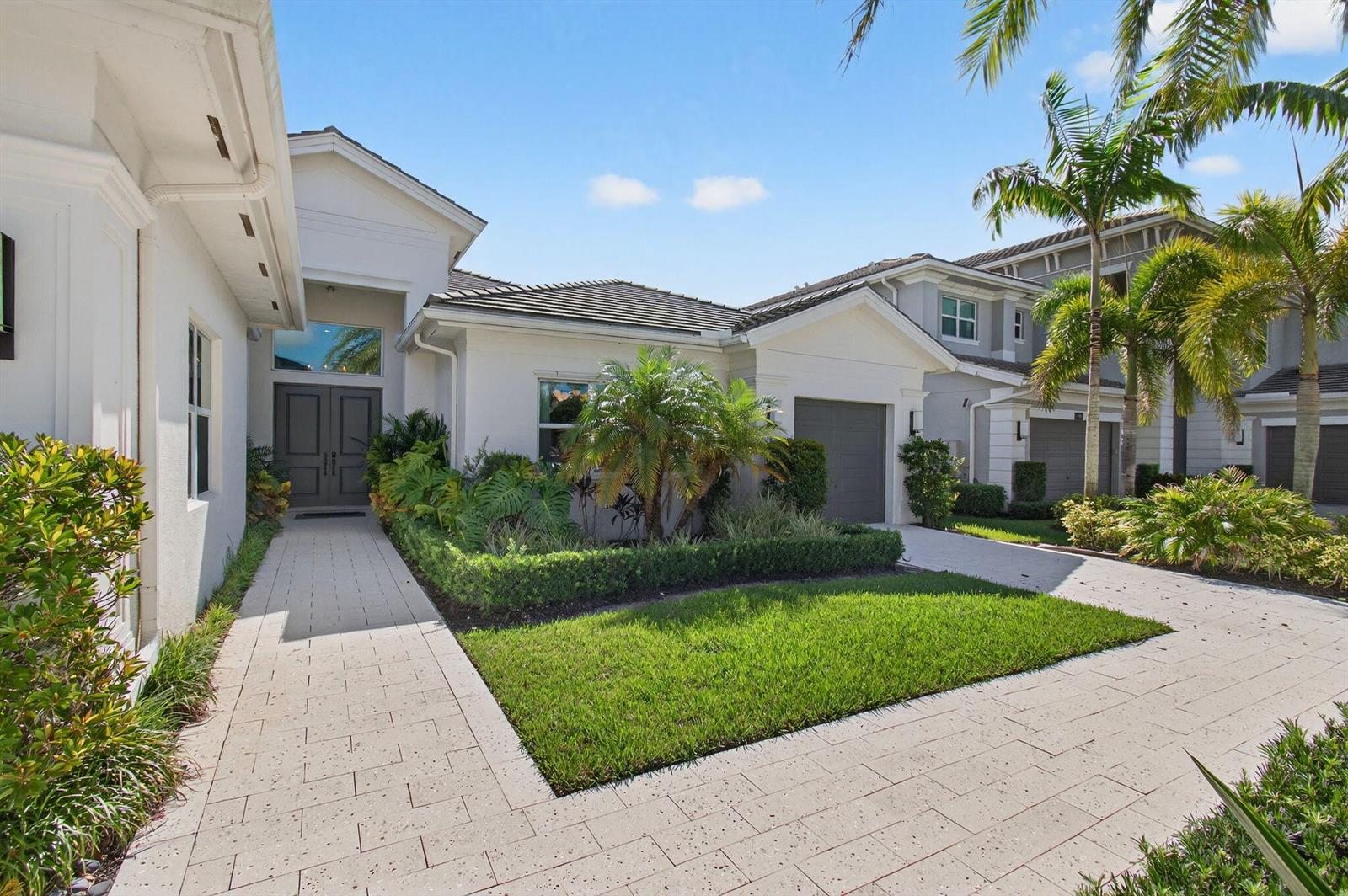A white house exterior features a paved walkway, a small lawn, and palm trees — 19886 Meadowside Lane Lane, Boca Raton FL 33498, BOCA RATON, FL