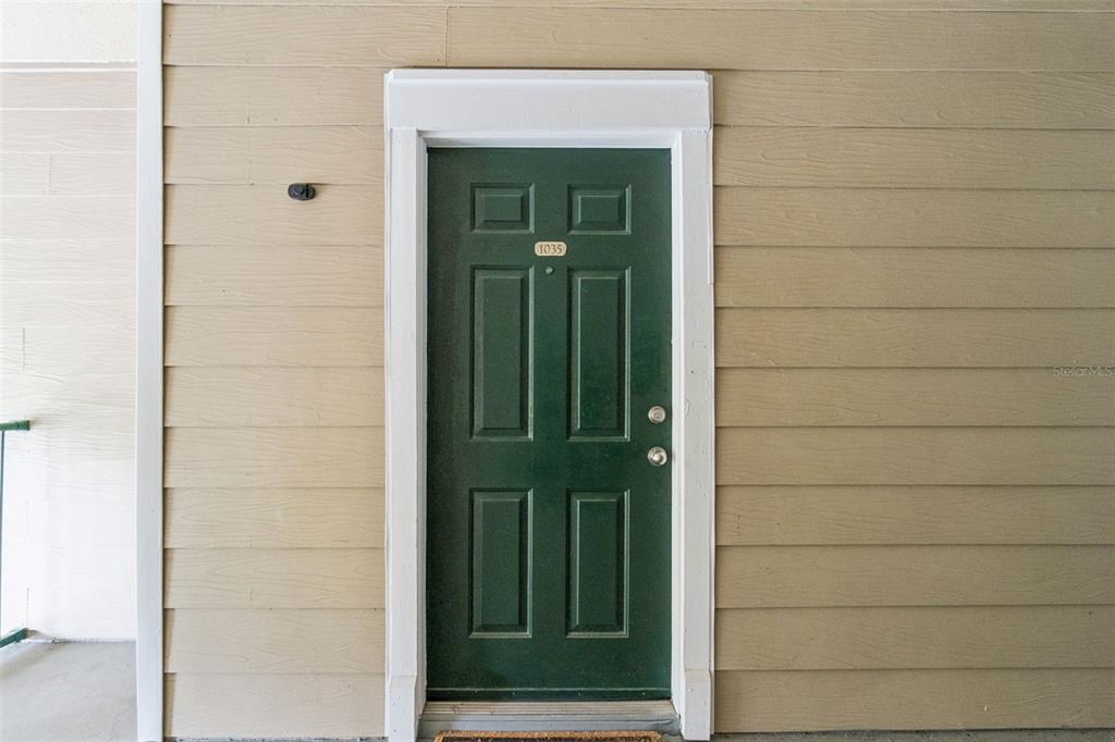 A green front door with the number 1035 is set in a tan horizontal-sided wall — 13015 PLANTATION PARK CIRCLE UNIT 1035, ORLANDO, FL
