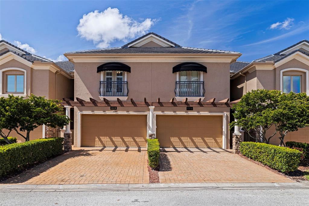 A two-story townhouse exterior features two garage doors, a pergola, and a brick driveway — 618 SAXONY BOULEVARD, ST PETERSBURG, FL