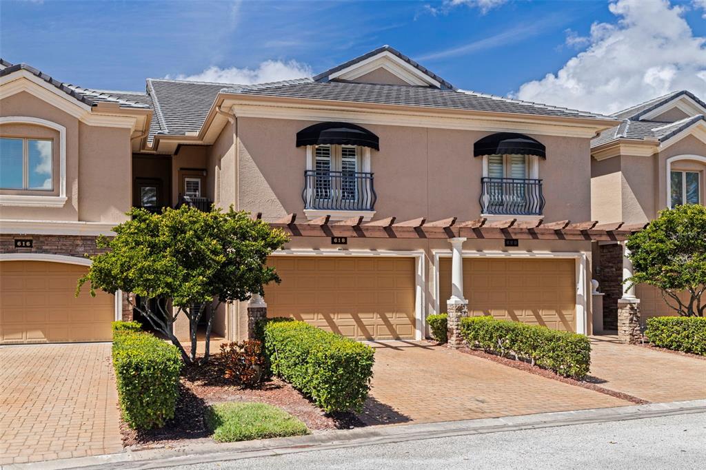 The exterior of a multi-unit residential building features tan stucco, garage doors, and arched windows — 618 SAXONY BOULEVARD, ST PETERSBURG, FL