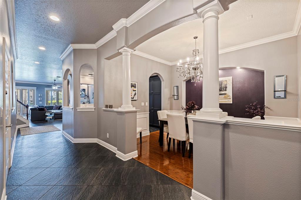 A dining room with a chandelier and dark accent wall sits beside a tiled hallway — 618 SAXONY BOULEVARD, ST PETERSBURG, FL