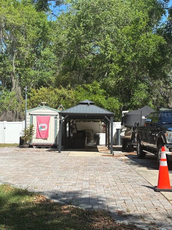 A paved driveway features a storage shed, a covered gazebo, and a parked truck with boat — 14415 252ND COURT ROAD NE UNIT 133, FORT MC COY, FL