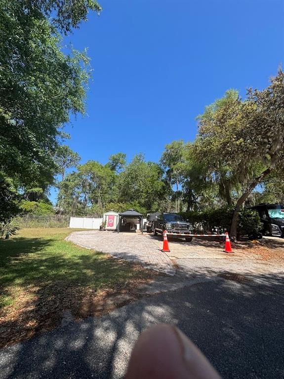 A paved driveway leads to a covered gazebo and a parked truck under mature trees — 14415 252ND COURT ROAD NE UNIT 133, FORT MC COY, FL
