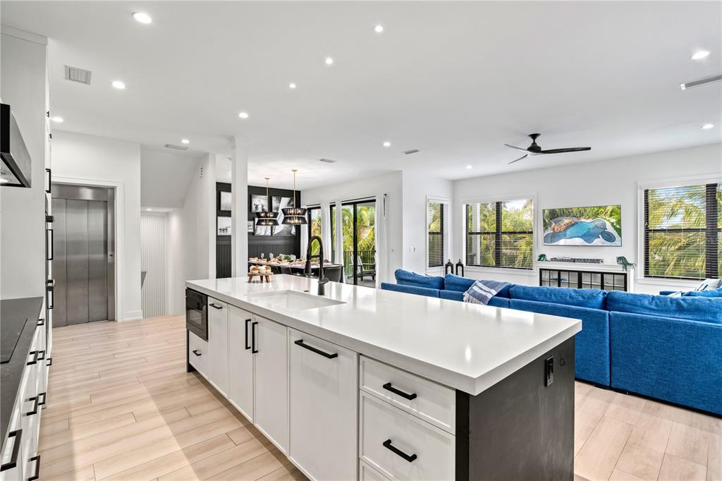 A modern kitchen with a large white island overlooks a living area with a blue sofa — 129 MCKINLEY DRIVE, SARASOTA, FL