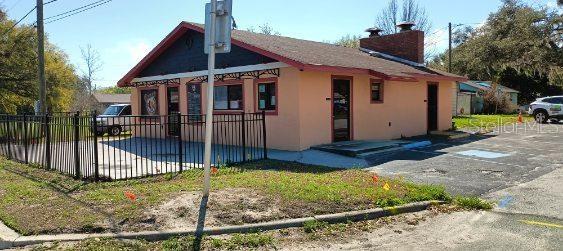 A single-story commercial building with peach-colored walls, a dark roof, and a black metal fence — 103 TAYLOR AVENUE, GROVELAND, FL