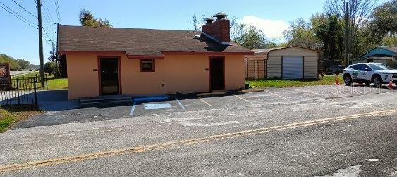 A single-story commercial building with a brick chimney and an adjacent metal storage shed — 103 TAYLOR AVENUE, GROVELAND, FL