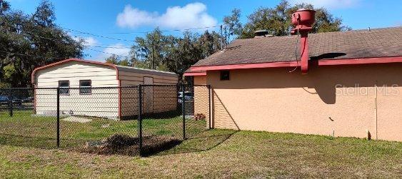 A tan house with a red roof and a detached metal shed in the backyard — 103 TAYLOR AVENUE, GROVELAND, FL