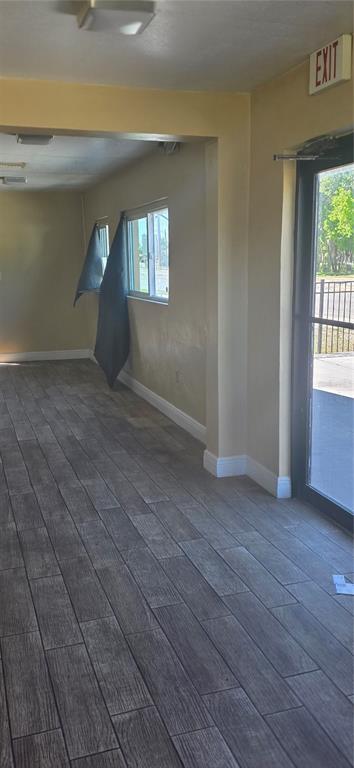 A room with wood-look tile flooring, beige walls, a window, and a glass exit door — 103 TAYLOR AVENUE, GROVELAND, FL