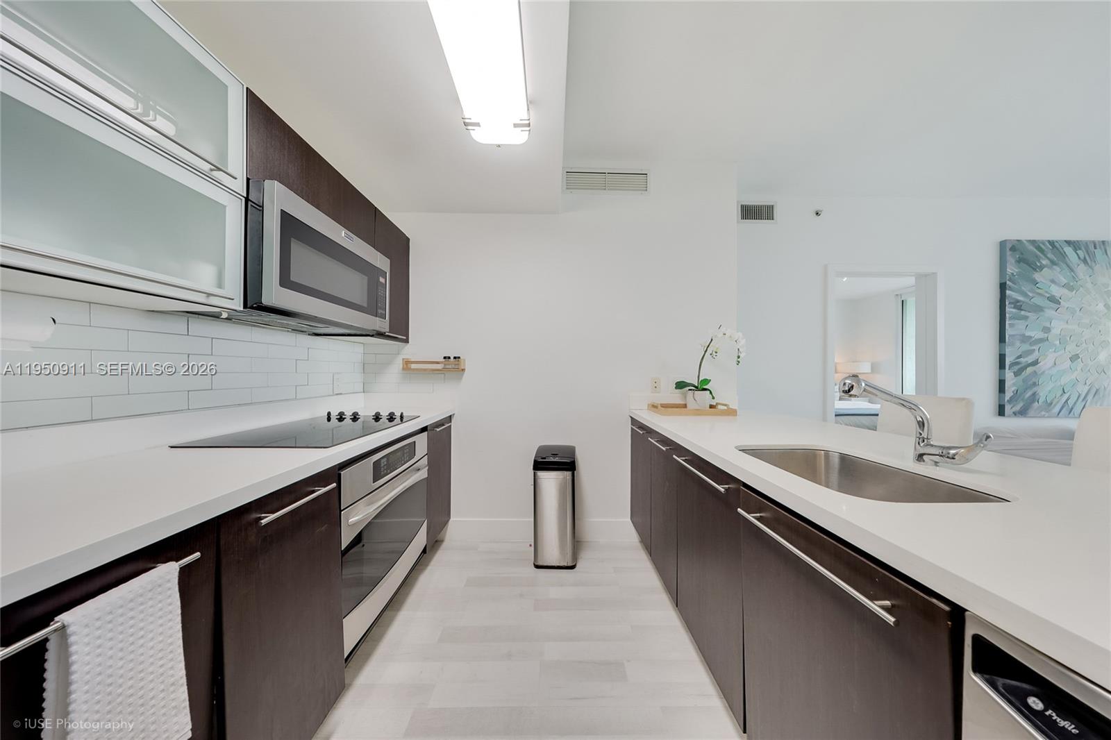A modern kitchen features dark wood cabinets, white countertops, stainless steel appliances, and tile backsplash — 90 SW 3rd St # 3109, Miami FL 33130, MIAMI, FL