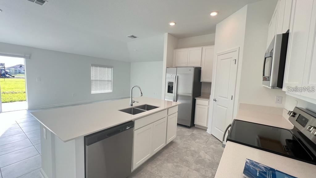 A kitchen with white cabinets, stainless steel appliances, and a large island with a sink — 263 BRAVE ROAD, DAVENPORT, FL