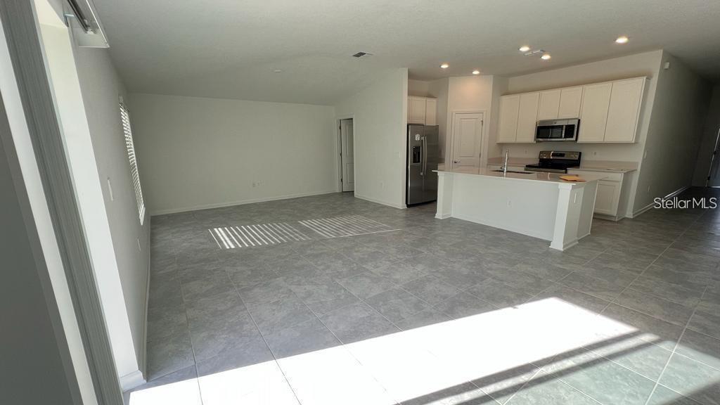 An open-concept kitchen with white cabinets and a center island overlooks a living area — 263 BRAVE ROAD, DAVENPORT, FL
