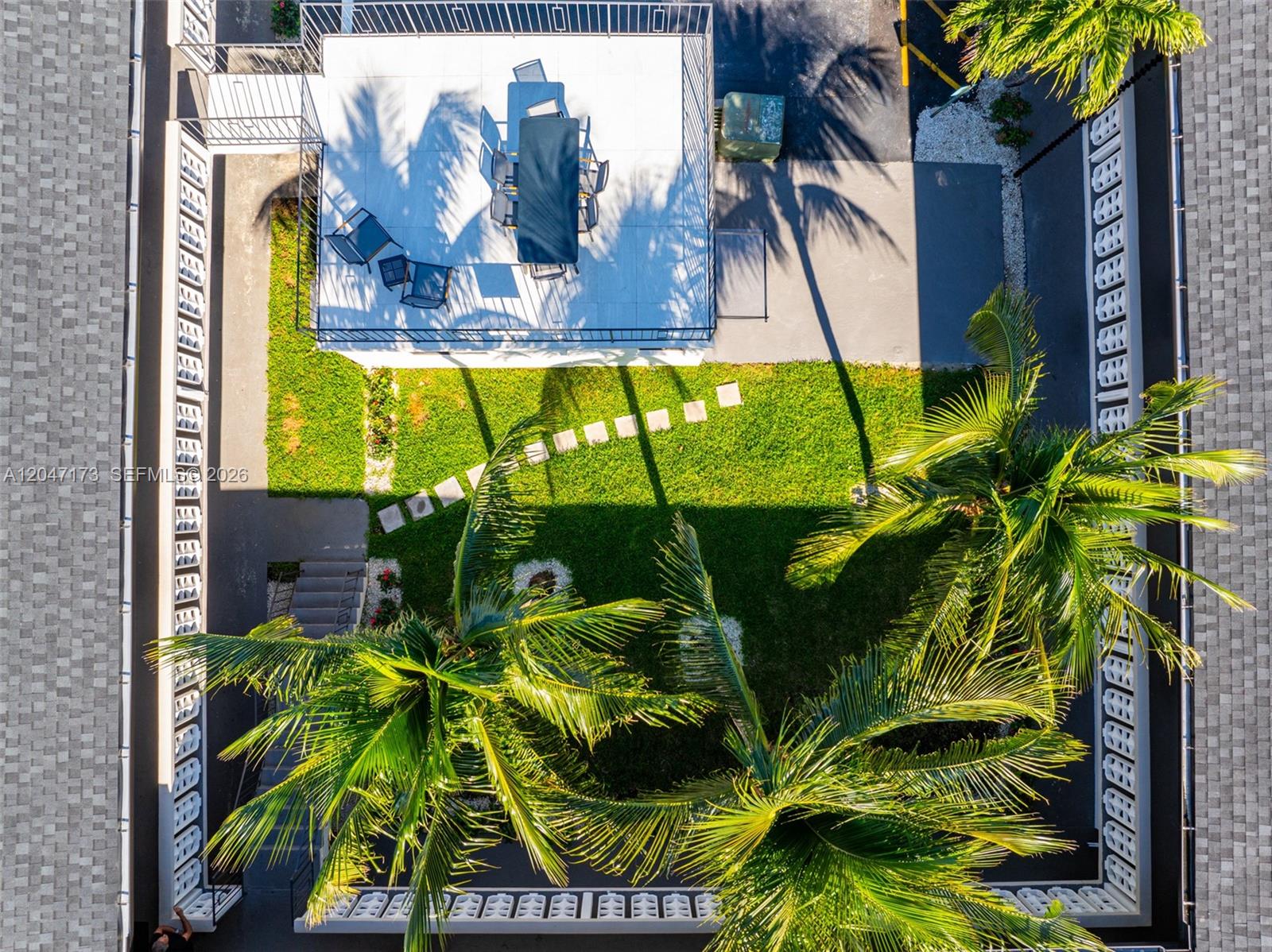 An aerial view shows a patio with outdoor furniture, a grassy lawn, and palm trees — 1330 W 29th St # 9, Hialeah FL 33012, HIALEAH, FL