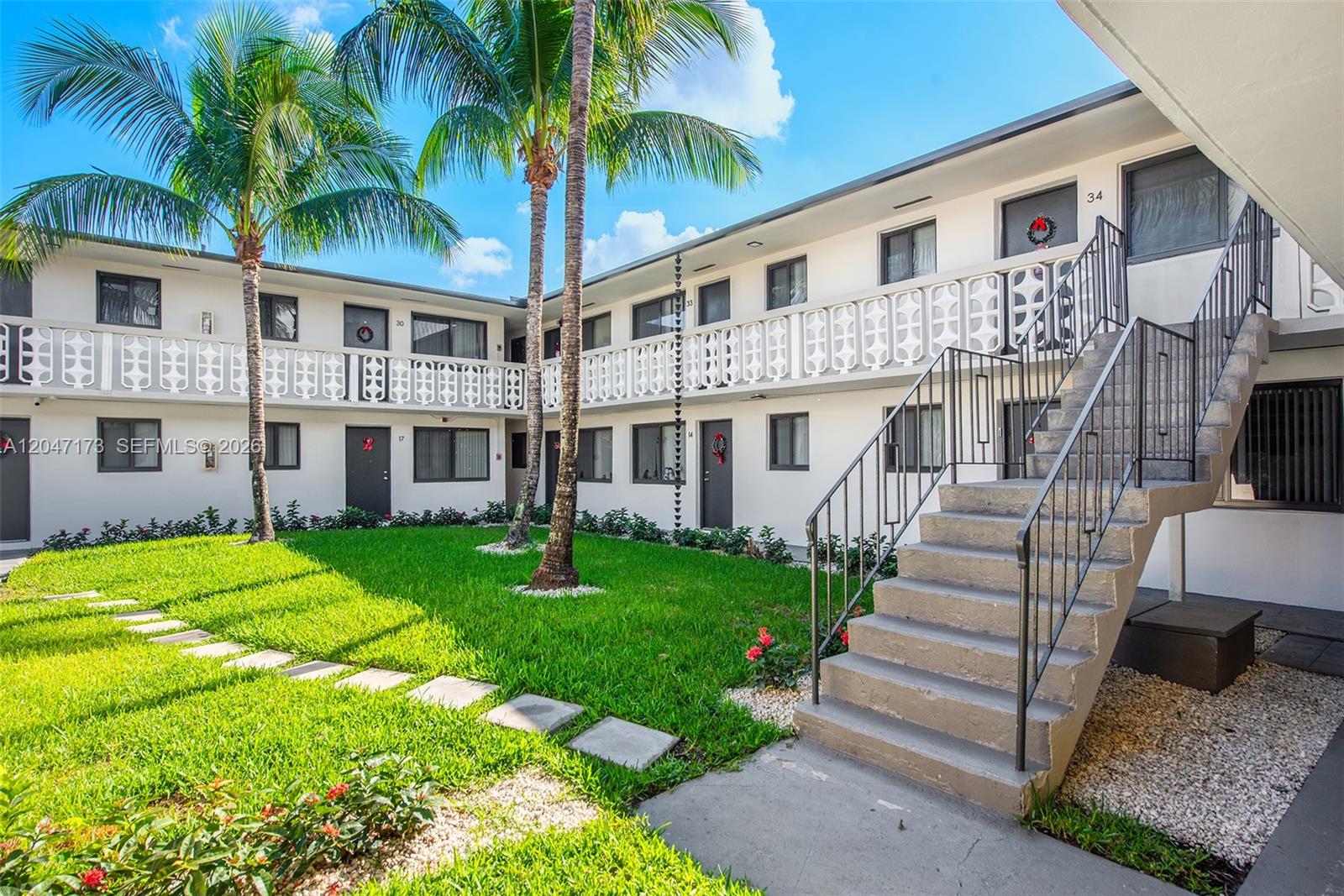 An exterior view of a two-story apartment building with a central courtyard and staircase — 1330 W 29th St # 9, Hialeah FL 33012, HIALEAH, FL