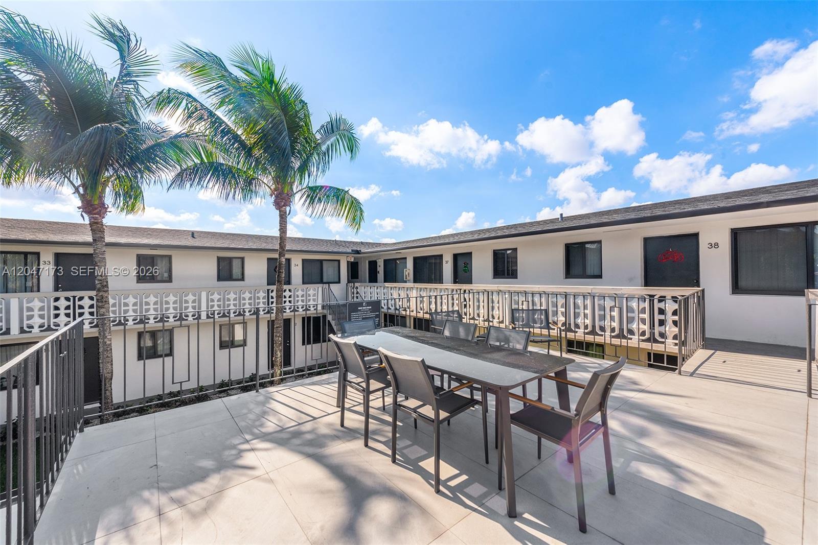 An outdoor patio features a dining table and chairs set against a two-story apartment building — 1330 W 29th St # 9, Hialeah FL 33012, HIALEAH, FL